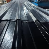 Stacked corrugated aluminium roofing sheets in a dark finish, showing the ribbed profile edge-on
