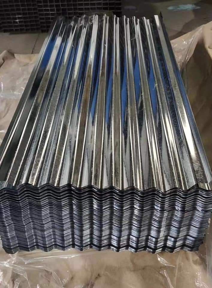 Stack of shiny galvanized corrugated metal roofing sheets wrapped for transport, showing the wave profile edge-on