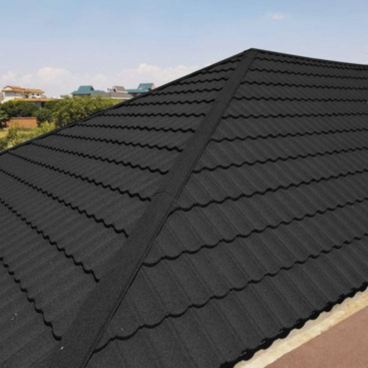Close-up of black stone-coated roof tiles showing the wavy profile and granule texture